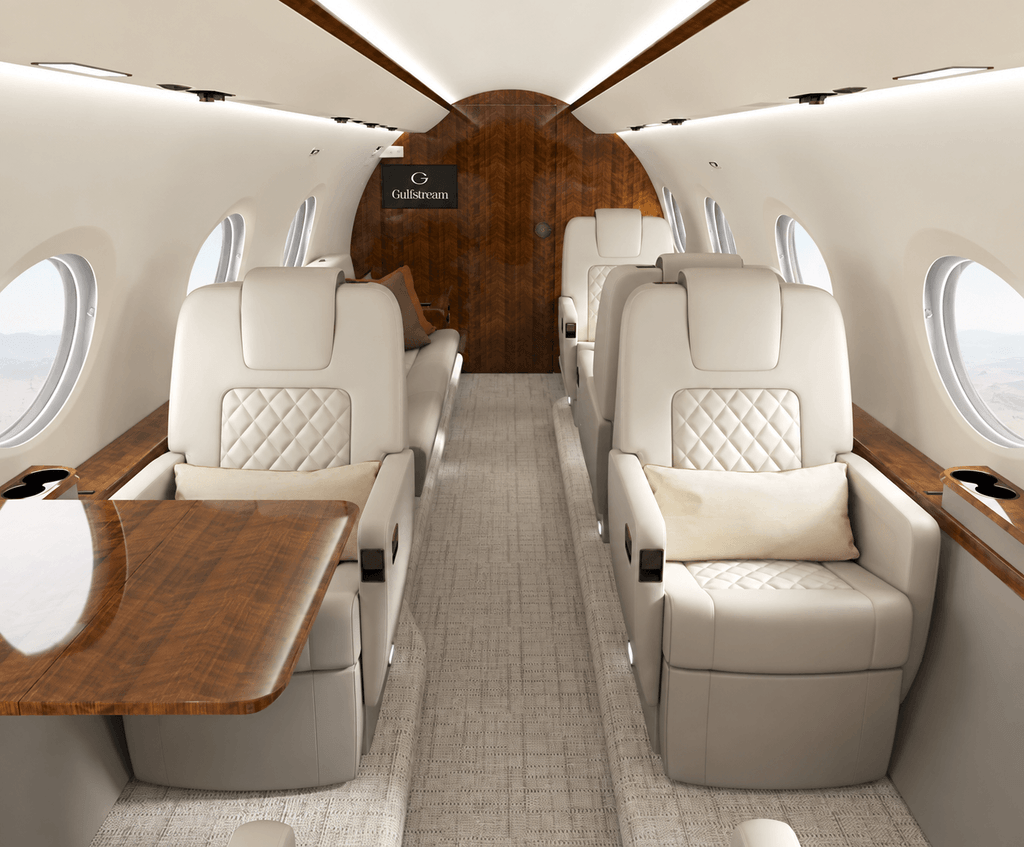 G280 cabin comparison for our Gulfstream G300 review, showing cream leather seats, polished wood tables and a subtle landscape through the windows.