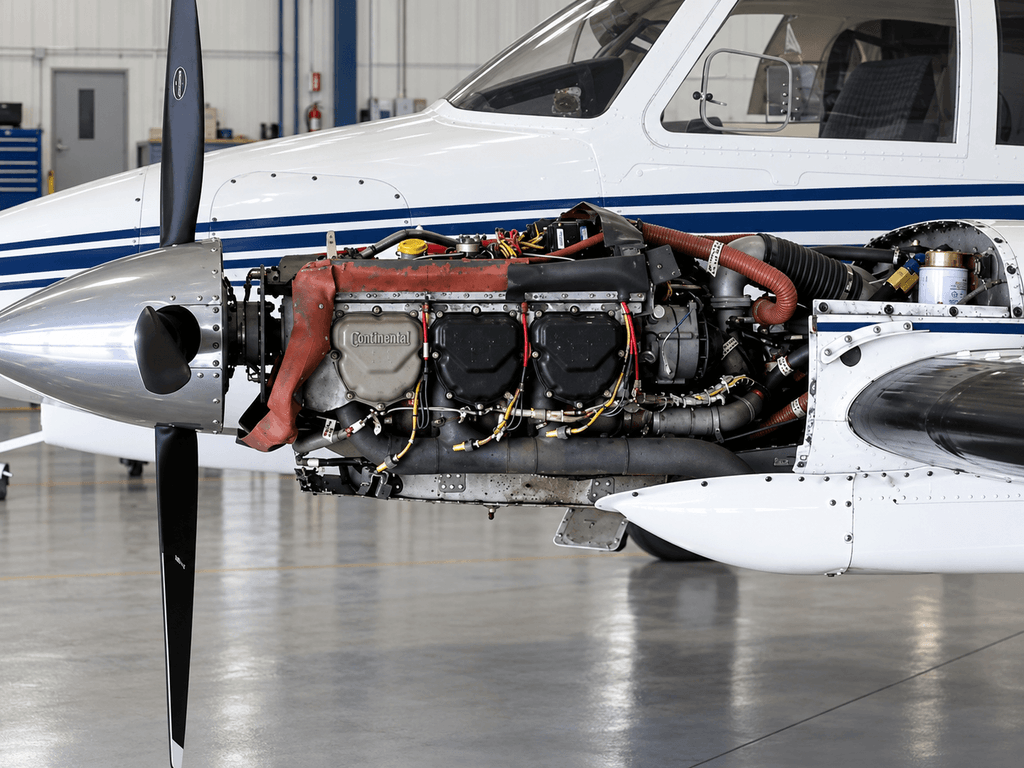 Exposed engine bay of a Cessna 310 twin engine aircraft inside a hangar.
